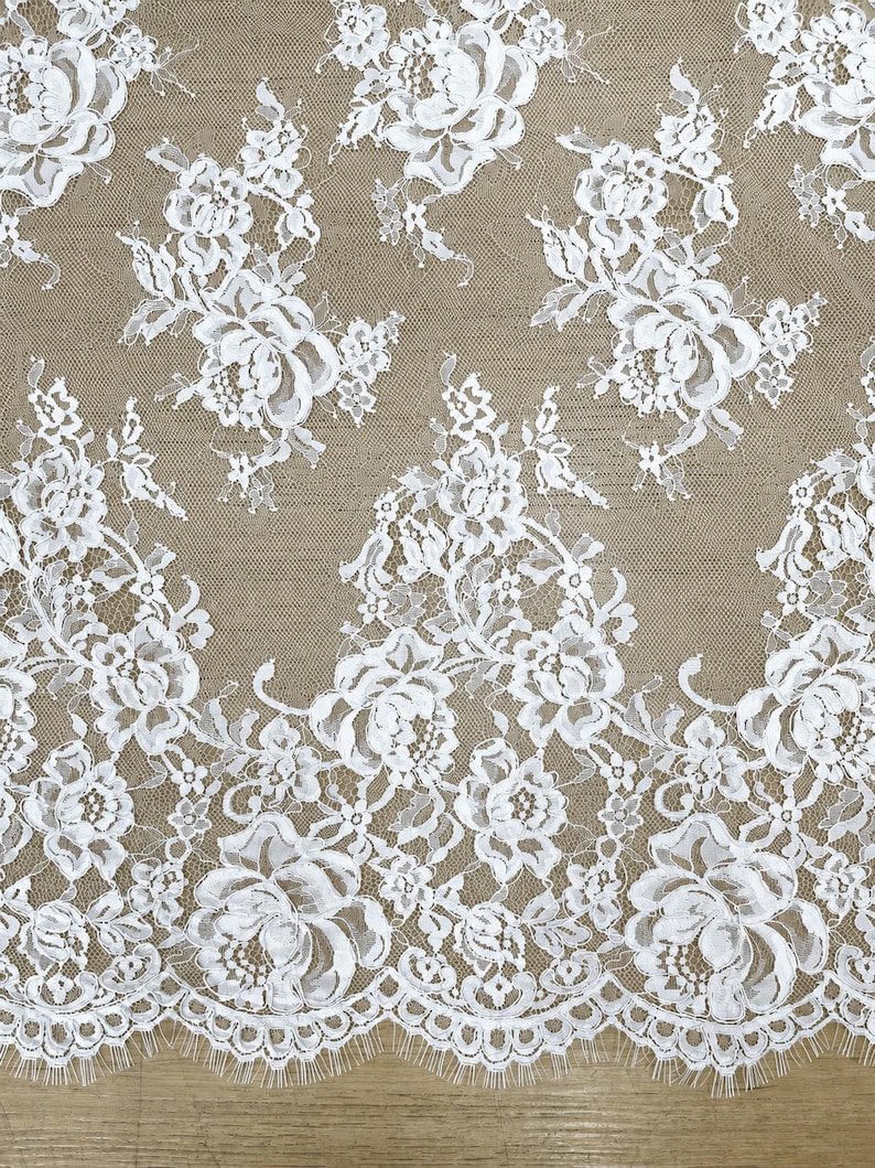 White lace fabric with white floral embroidery and a scalloped edge, perfect for a lace wedding gown.