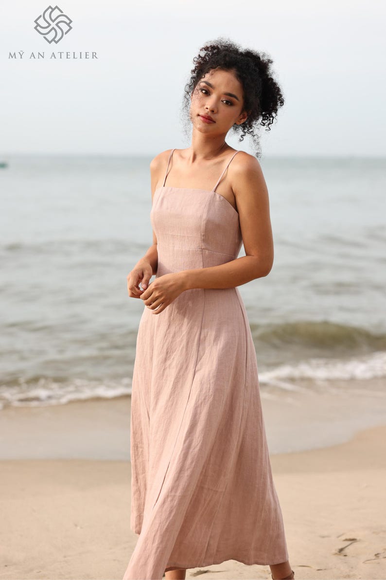 Medium shot from the waist up of a woman looking down thoughtfully, modeling a light mauve line