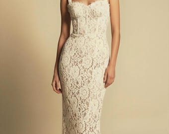 May include: Ivory lace gown with a fitted bodice and a floor-length skirt. The dress features a sweetheart neckline, wide shoulder straps, and a subtle waistline. The intricate floral lace pattern covers the entire dress, creating a romantic and elegant look.