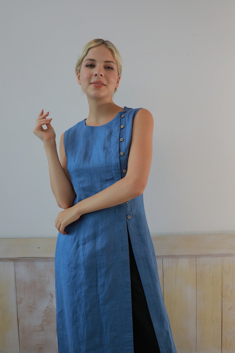 Medium front shot of the model looking into the camera with a gentle smile, emphasizing the textured weave of the organic blue linen fabric and a minimalist fashion style.