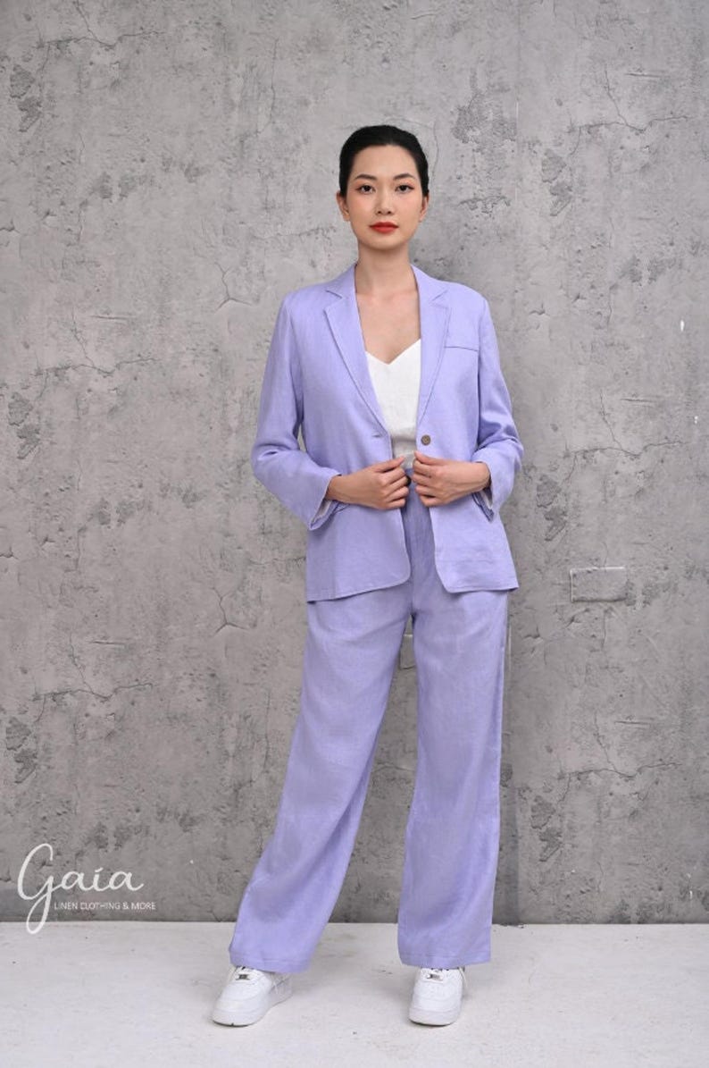 Front view of a model adjusting a lilac natural linen single-breasted jacket, emphasizing its clean two-button front silhouette and casual-chic corporate styling.