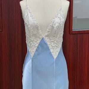 Front view close-up of the light blue satin dress on a mannequin, showcasing the precise points where the sheer lace meets the structured satin bodice.