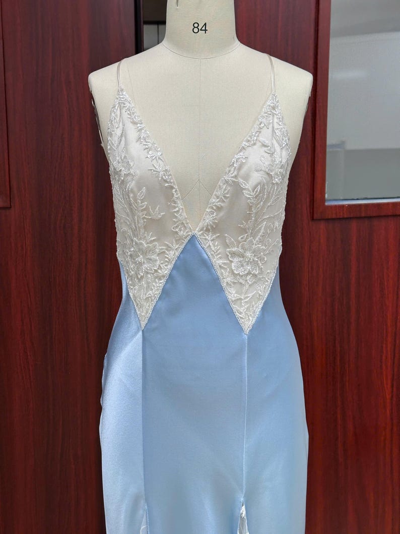 Front view close-up of the light blue satin dress on a mannequin, showcasing the precise points where the sheer lace meets the structured satin bodice.