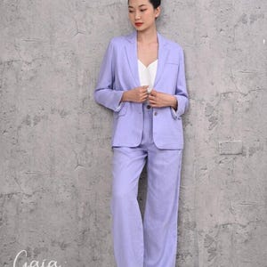 Front full-length view of a model standing in a custom-fit purple linen pantsuit, showcasing the relaxed fit, structured peak lapels, and smooth fall of the wide-leg pants.