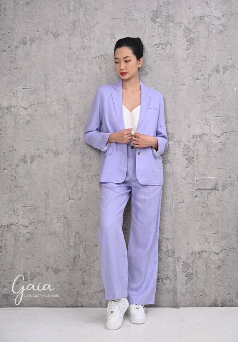 Front full-length view of a model standing in a custom-fit purple linen pantsuit, showcasing the relaxed fit, structured peak lapels, and smooth fall of the wide-leg pants.
