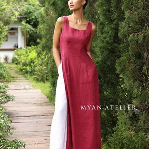 May include: A sleeveless, burgundy linen dress with a square neckline and a high side slit, paired with white linen pants. The text "MYAN ATELIER" is visible on the lower right. The model is standing on a wooden walkway.