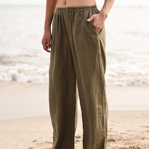 Three-quarter front shot of the model posing with one hand in her pocket on the beach, capturing the modern lifestyle vibe and comfortable versatility of the wide-leg design.