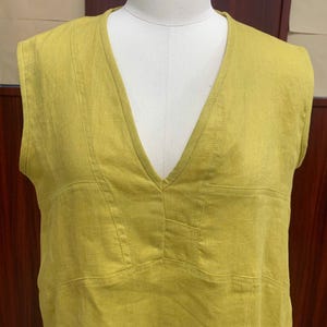 Close-up front shot focusing on the upper torso of the garment on the mannequin, emphasizing the neat stitching details around the deep V-neck and chest panel.