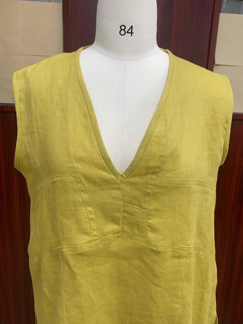 Close-up front shot focusing on the upper torso of the garment on the mannequin, emphasizing the neat stitching details around the deep V-neck and chest panel.