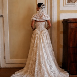 Custom ivory basque-waist lace wedding gown with corseted back, full train, and veil.