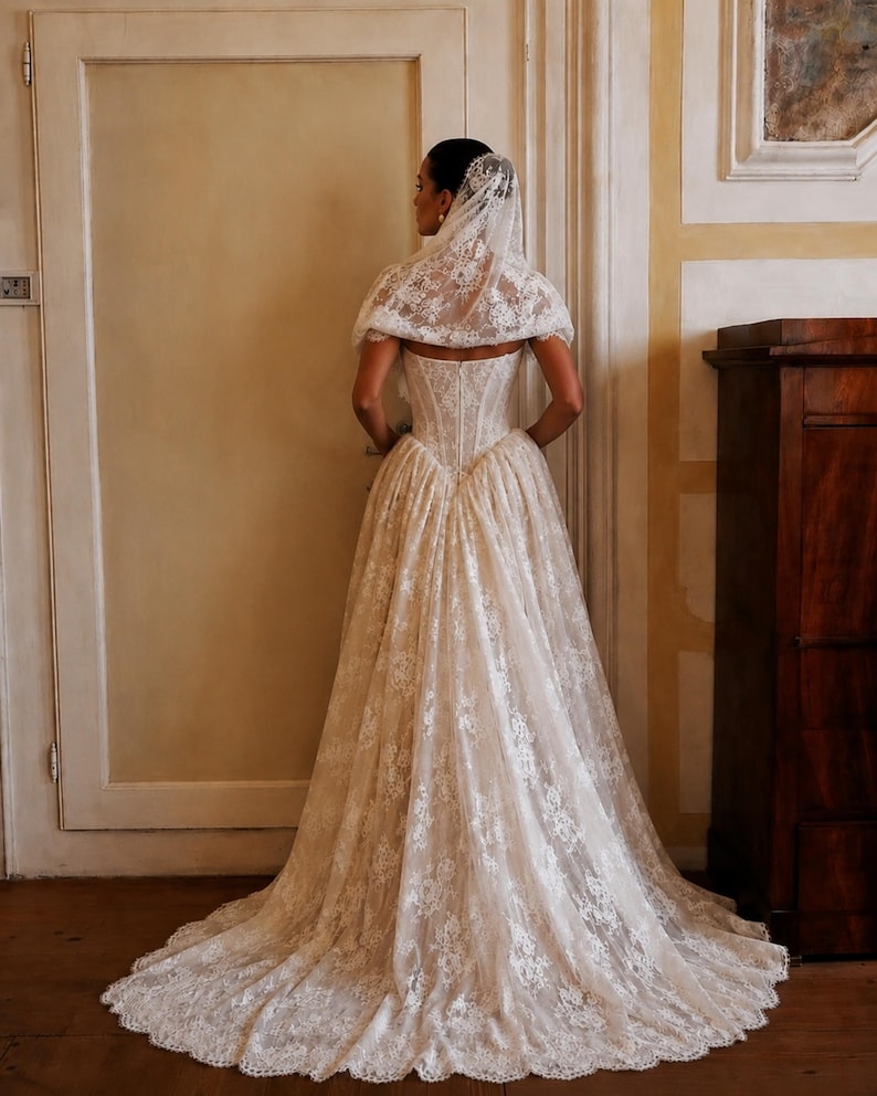 Custom ivory basque-waist lace wedding gown with corseted back, full train, and veil.