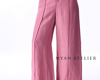 Könnte beinhalten: Zweiteiliges Outfit in Staubrosa. Das Ensemble umfasst eine Hose mit weitem Bein und ein passendes Oberteil. Die Hose hat eine hohe Taille und einen Knopfverschluss. Der Text "MYAN ATELIER" ist auf der Hose zu sehen.