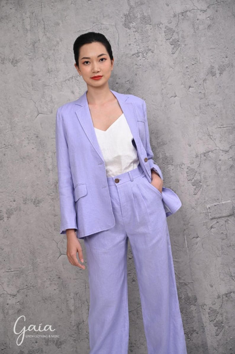 Mid-section shot of a woman modeling a custom-made lilac linen blazer jacket, highlighting the dual statement flap pockets at the waist and clean handcrafted French seams.