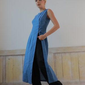 Full-length side view of the model looking slightly downward, demonstrating the dramatic high side slit that creates a modern, layered look with the black trousers.