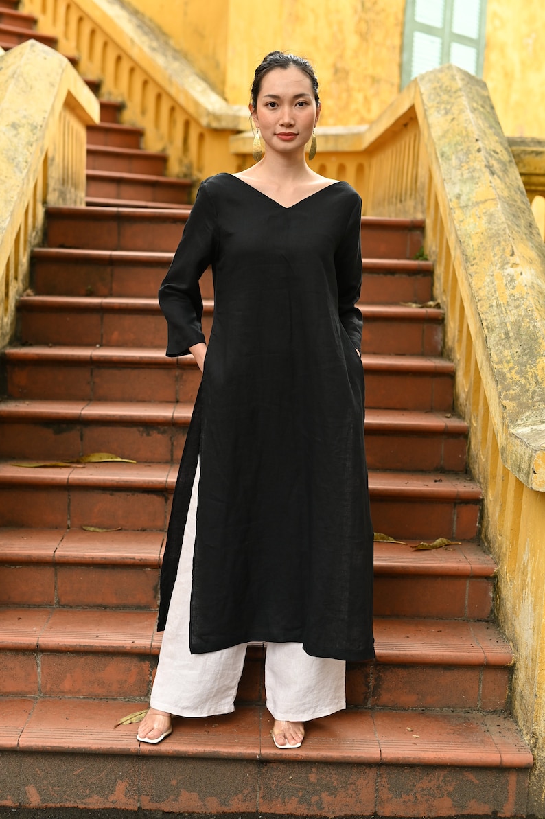Front full-length shot of the model standing on the terracotta steps, highlighting the minimalist design, comfortable loose fit, and high side slits of the black linen outfit.
