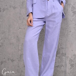 Close-up cropped shot of the high-waisted wide-leg linen trousers in light purple, highlighting the high-rise waistband detailed with front pleats and integrated deep side-seam pockets.