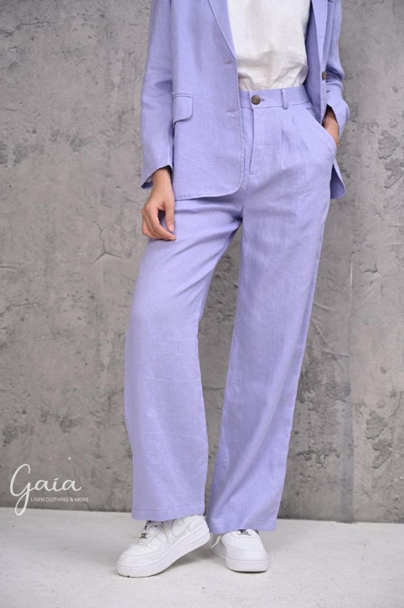 Close-up cropped shot of the high-waisted wide-leg linen trousers in light purple, highlighting the high-rise waistband detailed with front pleats and integrated deep side-seam pockets.