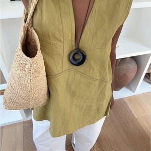 A high-angle selfie shot of the person wearing the chartreuse linen tunic, styled with a white trousers.