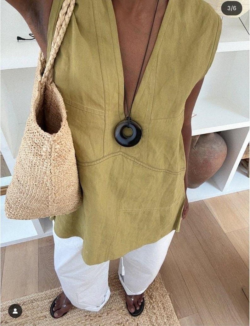 A high-angle selfie shot of the person wearing the chartreuse linen tunic, styled with a white trousers.