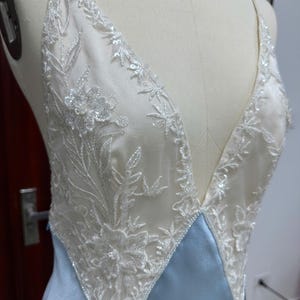 Detailed studio shot of the sheer lace bodice on a mannequin, highlighting the hand-applied lace details and deep V-neckline.
