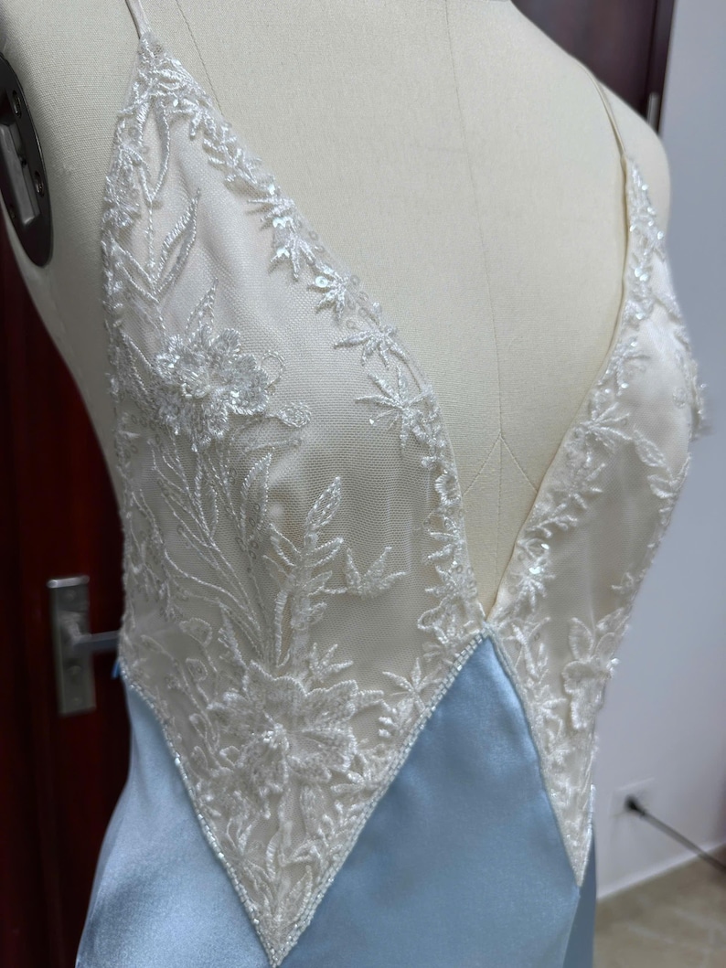 Detailed studio shot of the sheer lace bodice on a mannequin, highlighting the hand-applied lace details and deep V-neckline.