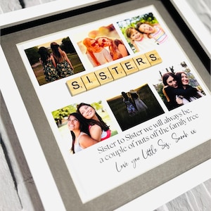 May include: A framed photo collage with multiple images of sisters, with the word "SISTERS" spelled out in wooden letter tiles. The bottom of the frame includes a handwritten message: "Sister to Sister we will always be, a couple of nuts off the family tree. Love you Little Sis, Sarah xx."
