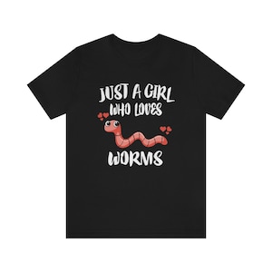 May include: Black t-shirt with white text that reads "Just a girl who loves worms". A cartoon worm with red body and black eyes is shown with hearts around it.