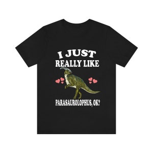 May include: Black t-shirt with white text that reads "I just really like Parasaurolophus, ok?" and a cartoon image of a Parasaurolophus dinosaur with pink hearts.