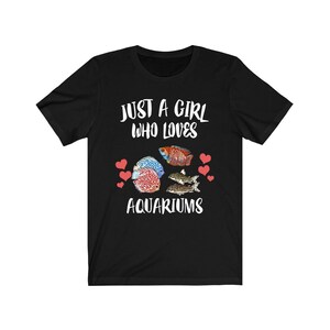May include: Black t-shirt with the text "Just a girl who loves aquariums" in white. The shirt features a colorful illustration of fish and hearts.