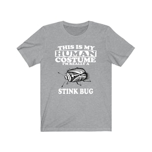 Op de afbeelding: Een grijs T-shirt met een witte afbeelding waarop staat "This is my human costume I'm really a stink bug" met een tekening van een stinkbug.