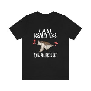 May include: Black t-shirt with a white graphic of a flying squirrel with hearts and the text "I just really like flying squirrels. Ok?"
