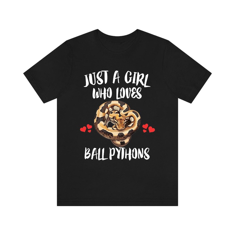 K&ouml;nnte beinhalten: Schwarzes T-Shirt mit dem wei&szlig;en Text "JUST A GIRL WHO LOVES BALL PYTHONS". Eine Grafik einer K&ouml;nigspython ist unter dem Text zentriert, mit zwei roten Herzen auf jeder Seite.