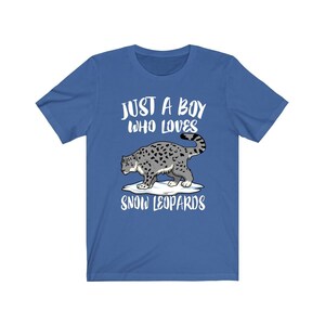 Pu&ograve; includere: Una t-shirt blu reale con una grafica bianca di un leopardo delle nevi che cammina su una macchia di neve. Il testo "Just a boy who loves snow leopards" &egrave; stampato in bianco sotto l'immagine.
