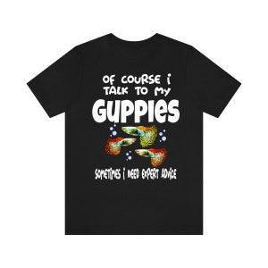 May include: Black t-shirt with the text "OF COURSE I TALK TO MY GUPPIES" in white. Below the text are three colorful guppy fish illustrations and the text "SOMETIMES I NEED EXPERT ADVICE".