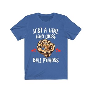 K&ouml;nnte beinhalten: Blaues T-Shirt mit dem Text "JUST A GIRL WHO LOVES BALL PYTHONS" in Wei&szlig;. Die Grafik zeigt eine zusammengerollte K&ouml;nigspython mit braunen und beigen Markierungen und zwei roten Herzen.