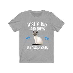 Peut inclure: Un t-shirt gris avec une illustration de chat siamois et le texte "JUST A BOY WHO LOVES JAVANESE CATS." Le design comprend des cœurs bleus. Le t-shirt est fait d'une matière douce.