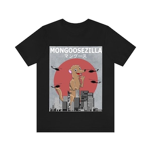 Puede incluir: Camiseta negra con una ilustración de dibujos animados de una mangosta en una ciudad, con helicópteros y un sol rojo de fondo. El texto "MONGOOSEZILLA" y caracteres japoneses están arriba.