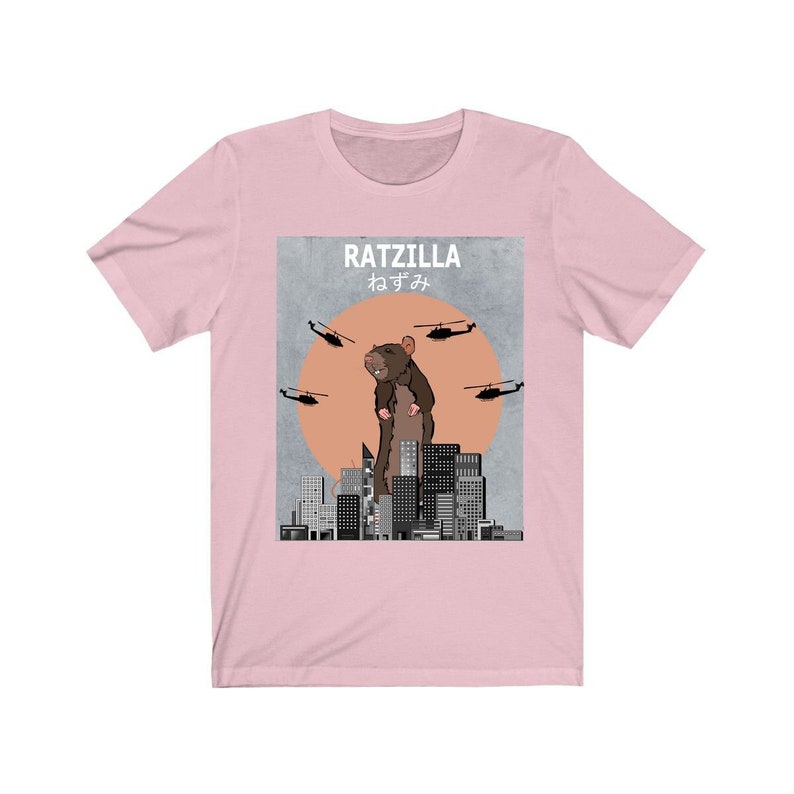 May include: Pink t-shirt with a graphic of a giant rat standing on a city skyline. The graphic says "RATZILLA" and "ねずみ" in Japanese.