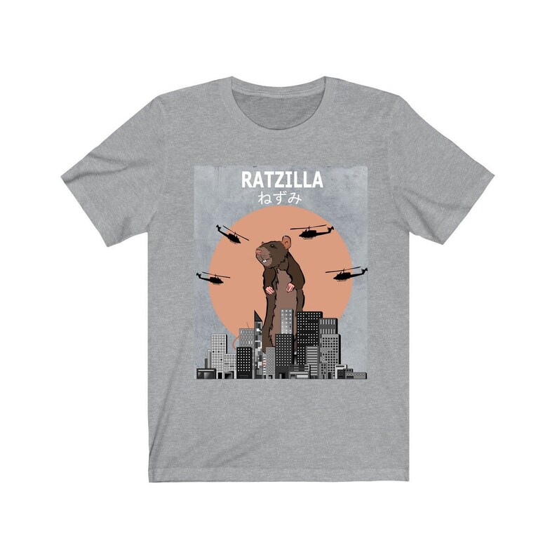 May include: A gray t-shirt with a graphic of a giant rat standing on a city skyline. The graphic says "Ratzilla" and "ねずみ" in Japanese. There are helicopters flying around the rat.