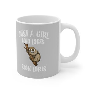 May include: A white ceramic mug with a grey design. The mug features a cartoon slow loris on a branch and the text "Just a girl who loves slow loris".