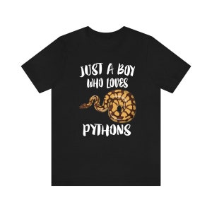 May include: Black t-shirt with white text that reads "Just a boy who loves pythons". A yellow and brown python is pictured on the shirt.