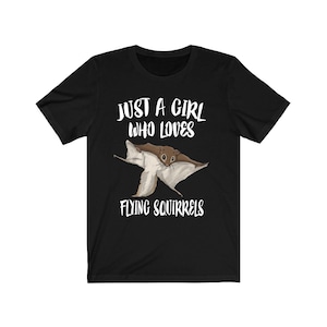 May include: Black t-shirt with white text that reads "Just a girl who loves flying squirrels". A cartoon flying squirrel is depicted in the centre of the shirt.