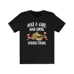 Puede incluir: Camiseta negra con texto blanco que dice "Just a girl who loves Burmese Pythons". Un gráfico de una pitón birmana se presenta con corazones rosas.