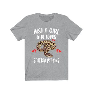 May include: A heather gray t-shirt with the text "JUST A GIRL WHO LOVES SPOTTED PYTHONS." The design features a spotted python illustration with red heart accents. The shirt is a casual wear item.