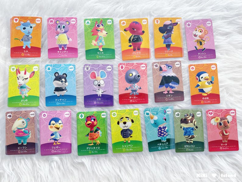 May include: A collection of Animal Crossing character trading cards. Each card features a different animal character with Japanese text and a unique design. The cards are arranged on a white, textured surface.