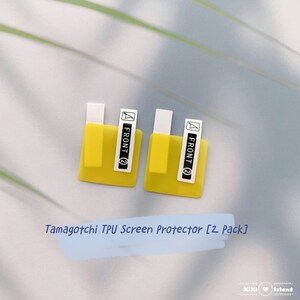 K&ouml;nnte beinhalten: Zwei gelbe Displayschutzfolien f&uuml;r ein Tamagotchi-Ger&auml;t. Jeder Schutz hat ein wei&szlig;es Etikett mit der Aufschrift "FRONT (2)". Der Text "Tamagotchi TPU Screen Protector [2 Pack]" steht unter den Schutzfolien.