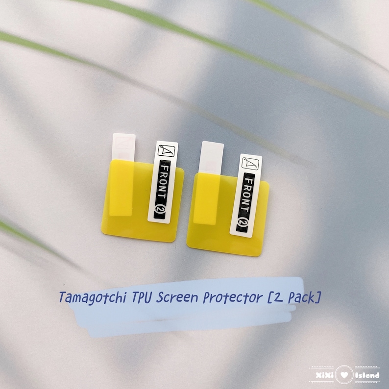 K&ouml;nnte beinhalten: Zwei gelbe Displayschutzfolien f&uuml;r ein Tamagotchi-Ger&auml;t. Jeder Schutz hat ein wei&szlig;es Etikett mit der Aufschrift "FRONT (2)". Der Text "Tamagotchi TPU Screen Protector [2 Pack]" steht unter den Schutzfolien.