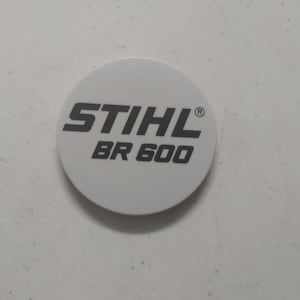 Puede incluir: Pegatina redonda blanca con texto negro que dice "STIHL BR 600" con un símbolo de marca registrada.