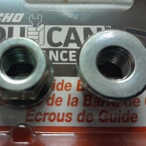 Può includere: Due dadi in metallo argentato, uno con forma esagonale e l'altro con forma rotonda. I dadi sono per una barra guida per motosega.