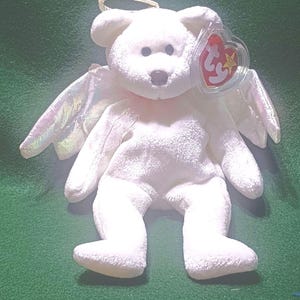 May include: White plush angel bear with iridescent wings and a halo. The bear has a red heart-shaped tag with the Ty logo and a star.
